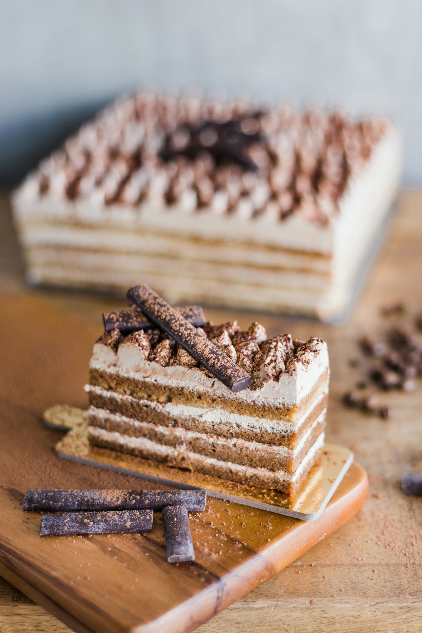 Slice of layered almond cake with cream served on a wooden board
