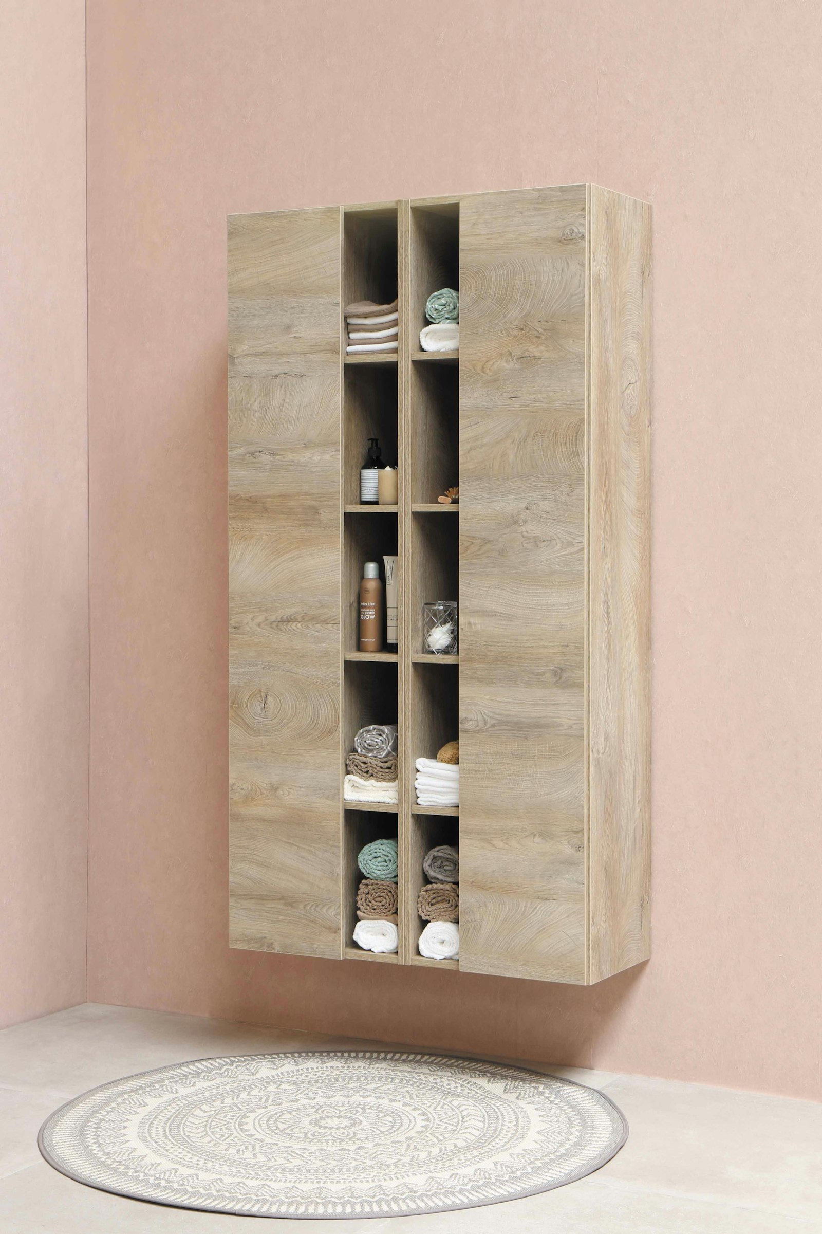 Tall modular wooden Cubit shelving unit standing against a pink wall
