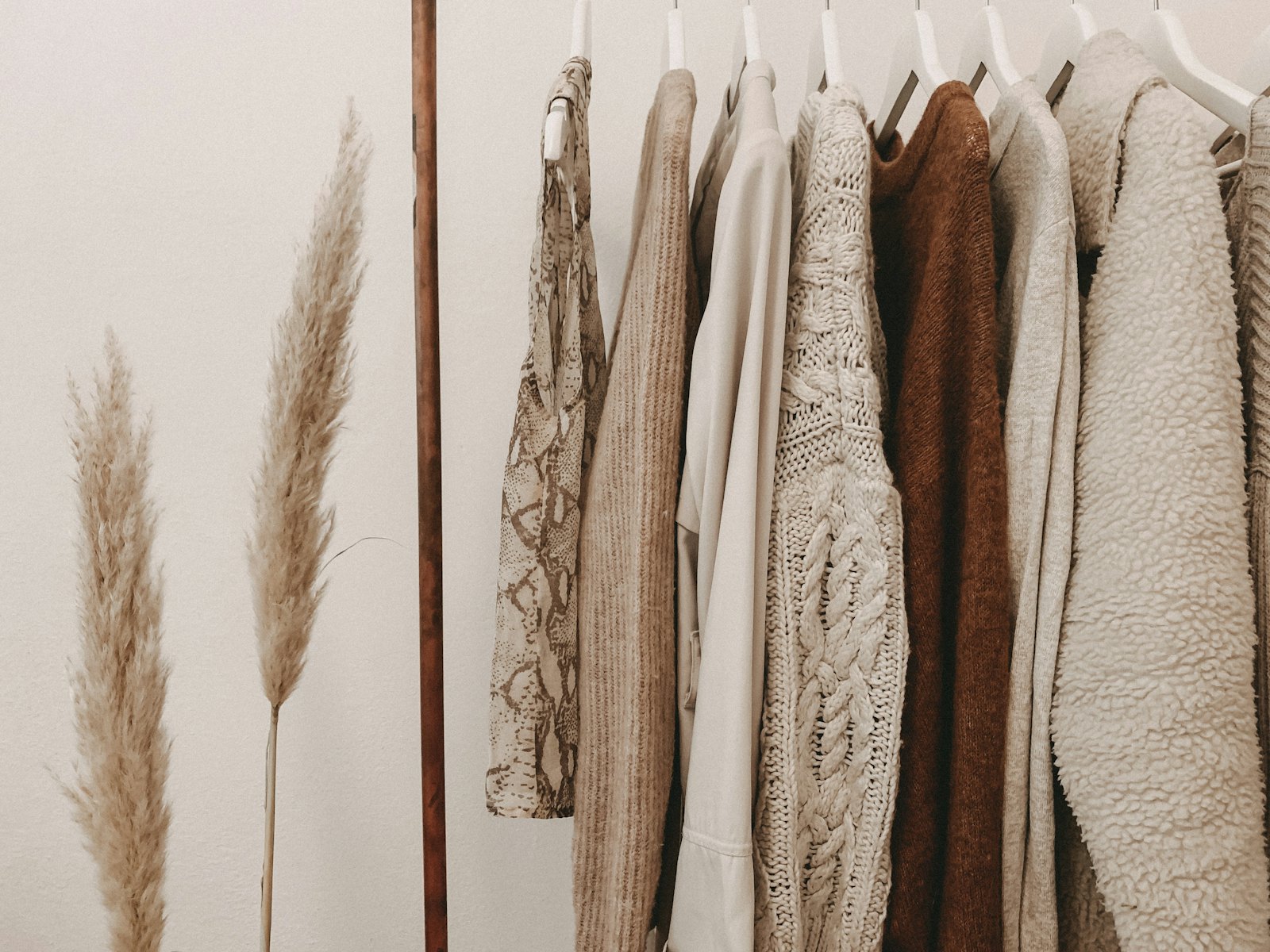 Knitted and woven wool textiles hanging beside dried pampas grass, evoking Eleanor Pritchard textiles