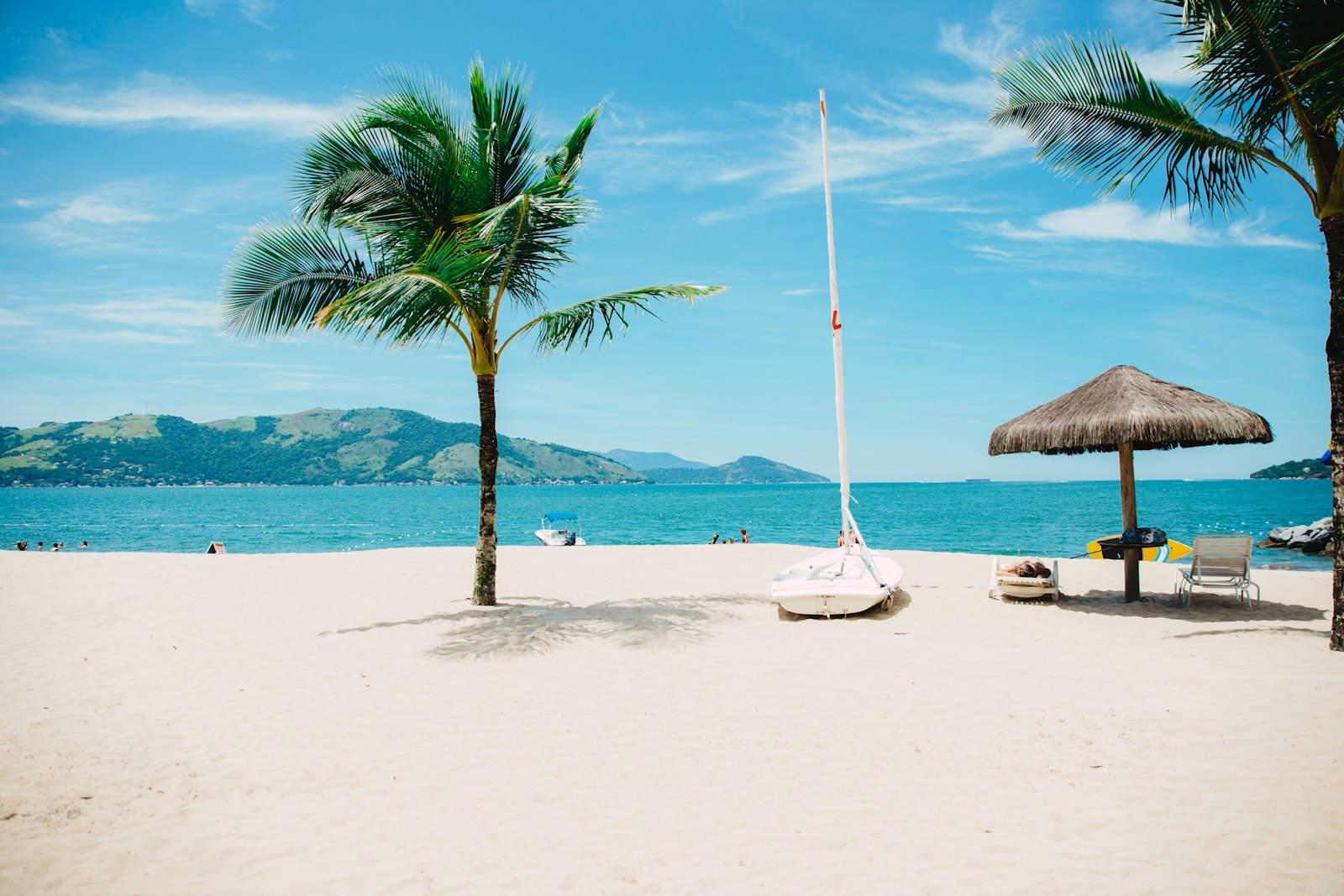 Tropical beach with palm trees and a thatched parasol, the dream setting for heavenly hammocks