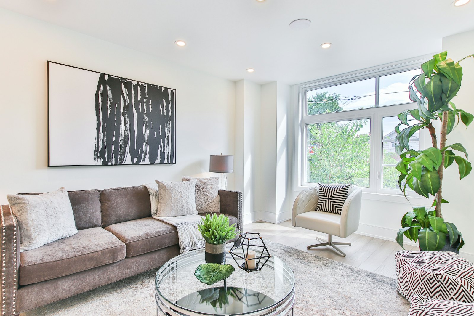 Airy living room with a grey sofa, large black-and-white artwork and green plants, in the spirit of the House of Fraser Christiane Lemieux range