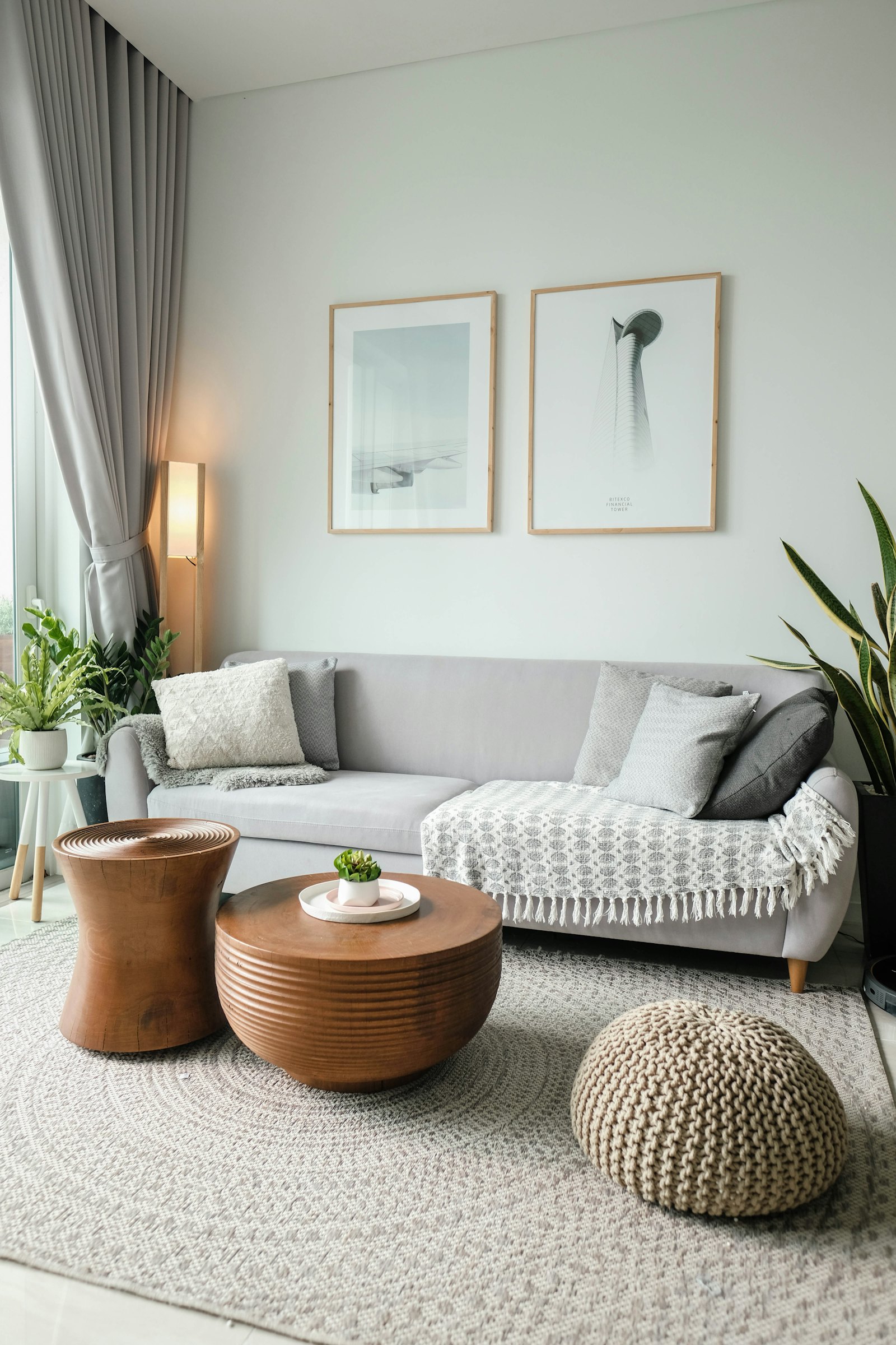 Calm living room with a pale sofa, round wooden side tables and framed botanical prints, in the House of Twenty style