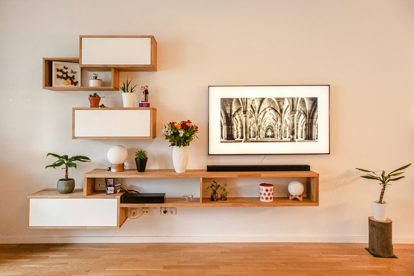 Floating wooden open kitchen shelves with plants and objects against a pale wall