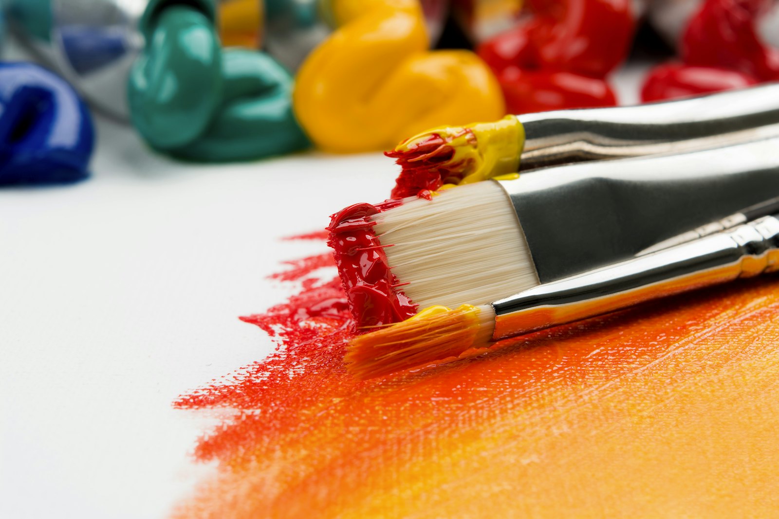 Artist's paintbrush loaded with bright orange and yellow paint, ready for a tennis racket upcycle project